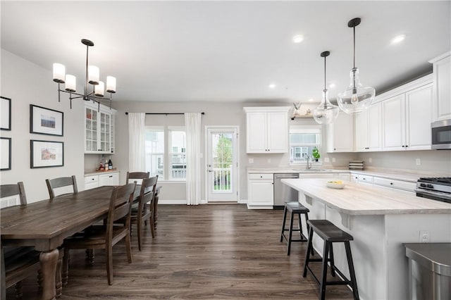kitchen with a sink, an inviting chandelier, stainless steel appliances, and white cabinetry