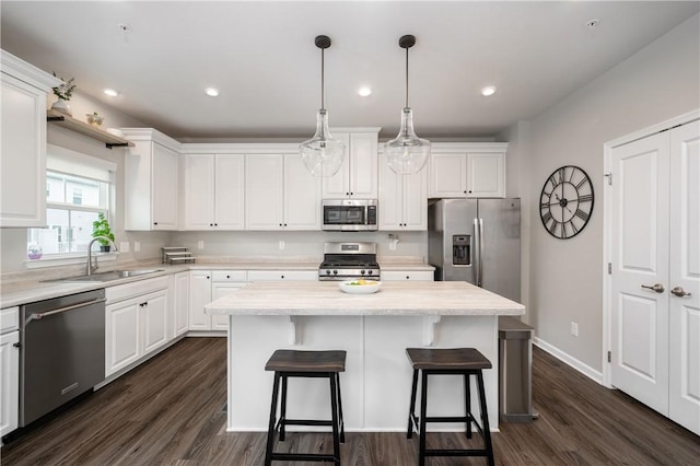 kitchen featuring a center island, a sink, white cabinets, a breakfast bar, and stainless steel appliances
