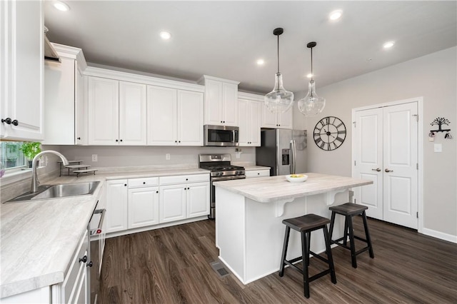 kitchen with a sink, light countertops, stainless steel appliances, white cabinetry, and dark wood-type flooring