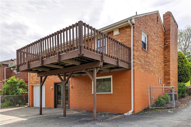 rear view of property featuring a chimney, concrete block siding, fence, and a deck