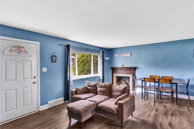 living area with baseboards, visible vents, wood finished floors, and a fireplace