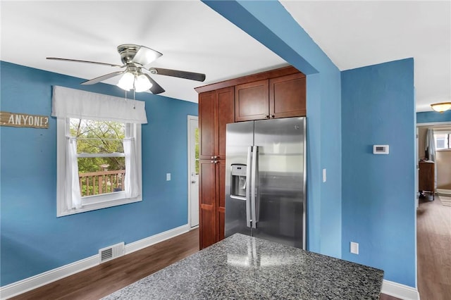 kitchen featuring a ceiling fan, visible vents, dark wood finished floors, baseboards, and stainless steel fridge