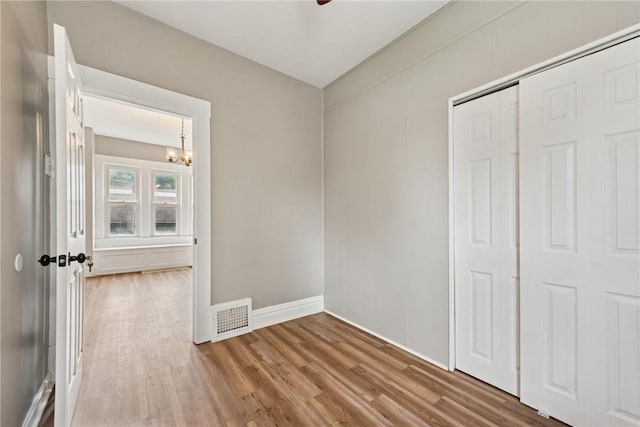 410 Butz St, New Castle/3Rd, PA 16101 - unfurnished bedroom featuring an inviting chandelier, baseboards, wood finished floors, visible vents, and a closet