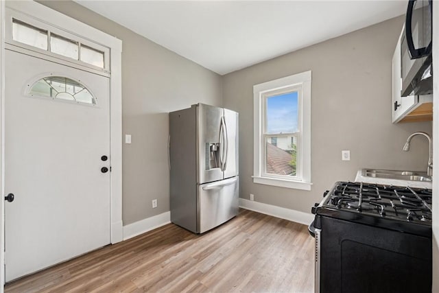 410 Butz St, New Castle/3Rd, PA 16101 - kitchen with baseboards, gas range, light wood-type flooring, stainless steel fridge with ice dispenser, and a sink