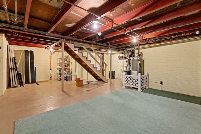 unfinished basement with stairway, gas water heater, and brick wall