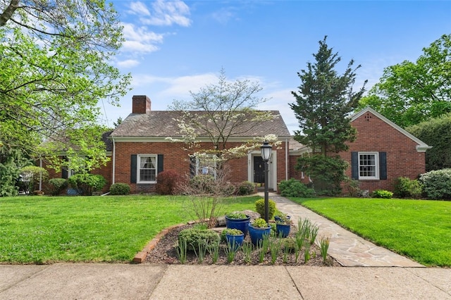 view of front facade with a chimney, brick siding, and a front yard
