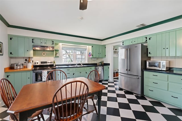 kitchen featuring visible vents, dark countertops, stainless steel appliances, dark floors, and under cabinet range hood