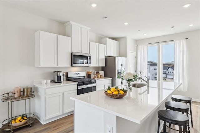 177 Sweetwater Dr, Moon/Crescent Twp, PA 15108 - kitchen featuring a breakfast bar, light wood finished floors, an island with sink, stainless steel appliances, and white cabinetry