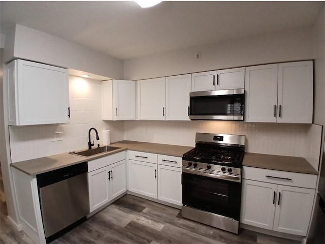 2318 Salisbury St, South Side, PA 15210 - kitchen featuring decorative backsplash, dark wood-style flooring, white cabinetry, a sink, and appliances with stainless steel finishes