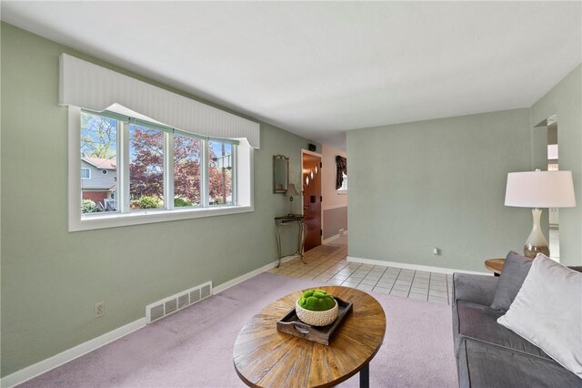 living area with visible vents, carpet flooring, baseboards, and tile patterned flooring