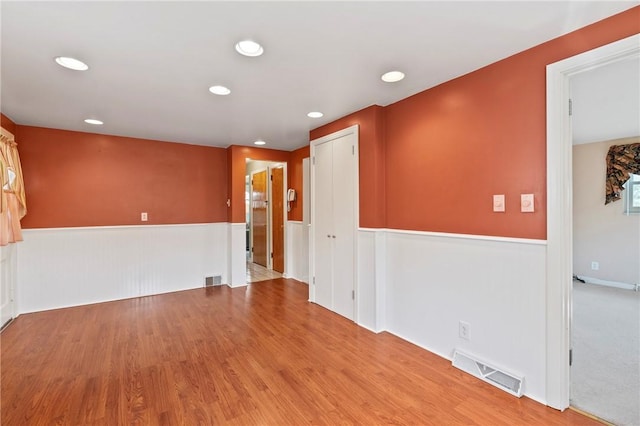 empty room featuring wainscoting, recessed lighting, wood finished floors, and visible vents