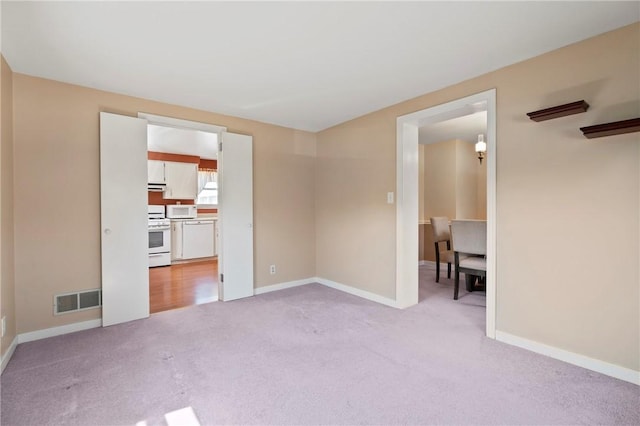unfurnished room with visible vents, baseboards, and light carpet