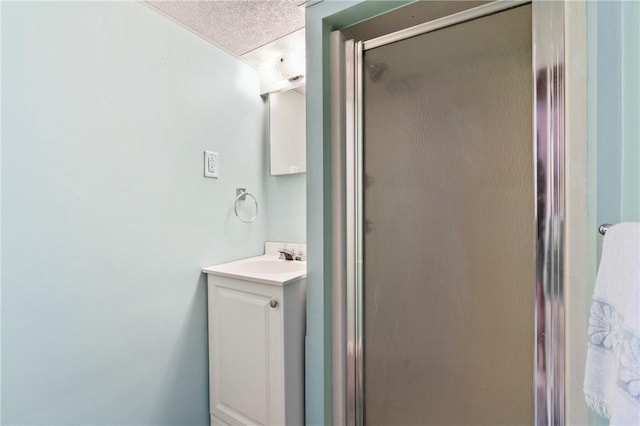 bathroom featuring a textured ceiling, a shower stall, and vanity