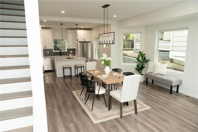 dining space with recessed lighting, baseboards, wood finished floors, and stairway