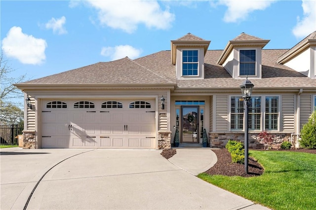 view of front of house with a garage, a front yard, stone siding, a shingled roof, and concrete driveway
