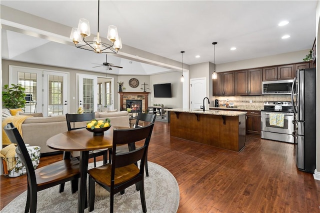 dining area featuring a glass covered fireplace, recessed lighting, ceiling fan with notable chandelier, and dark wood finished floors