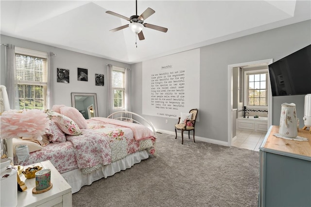 bedroom with baseboards, multiple windows, ensuite bathroom, and light colored carpet