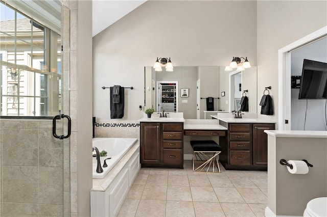 full bath featuring a garden tub, a stall shower, two vanities, high vaulted ceiling, and tile patterned floors