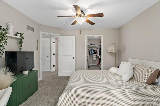 bedroom with carpet floors, visible vents, a closet, baseboards, and a walk in closet