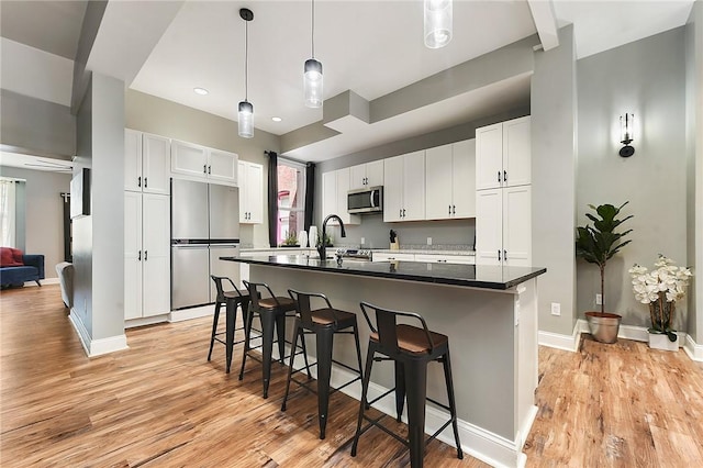 308 Jacksonia St, Central North Side, PA 15212 - kitchen featuring white cabinets, appliances with stainless steel finishes, a breakfast bar, and light wood-style floors