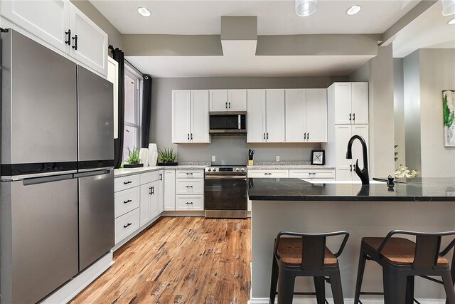 308 Jacksonia St, Central North Side, PA 15212 - kitchen featuring light wood-style floors, a breakfast bar area, stainless steel appliances, and white cabinetry