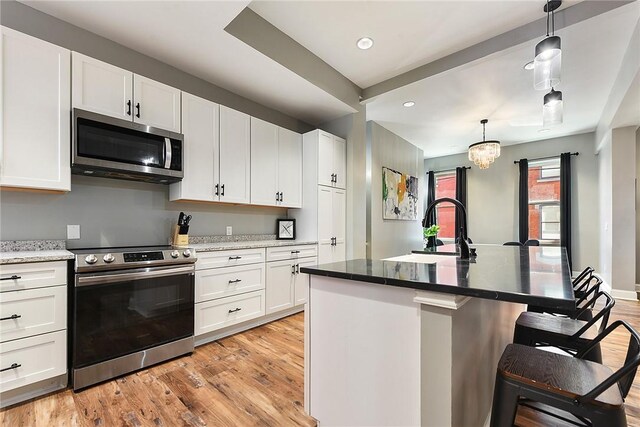 308 Jacksonia St, Central North Side, PA 15212 - kitchen with light wood-style flooring, appliances with stainless steel finishes, a kitchen breakfast bar, and white cabinetry