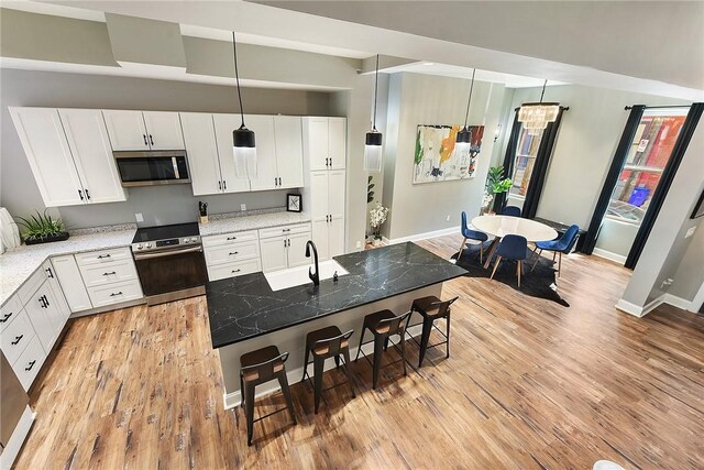 308 Jacksonia St, Central North Side, PA 15212 - kitchen featuring baseboards, a breakfast bar area, white cabinetry, light wood finished floors, and stainless steel appliances