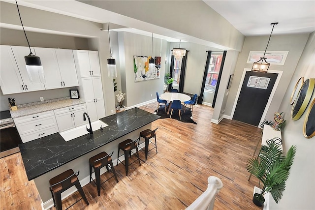 308 Jacksonia St, Central North Side, PA 15212 - kitchen featuring white cabinets, a sink, light wood finished floors, a kitchen breakfast bar, and baseboards