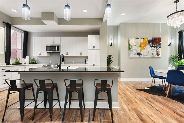 308 Jacksonia St, Central North Side, PA 15212 - kitchen with a breakfast bar, a sink, light wood-style flooring, baseboards, and stainless steel microwave