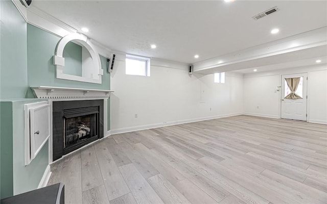 unfurnished living room featuring a fireplace, recessed lighting, light wood-style flooring, and visible vents
