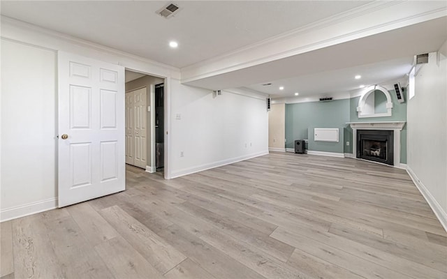 unfurnished living room featuring visible vents, light wood-type flooring, baseboards, ornamental molding, and recessed lighting