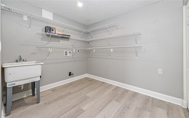 clothes washing area with baseboards, laundry area, light wood finished floors, and hookup for a washing machine