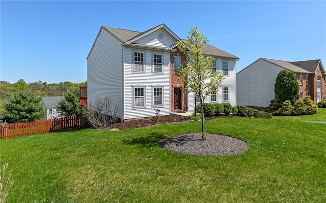 colonial inspired home with fence and a front yard