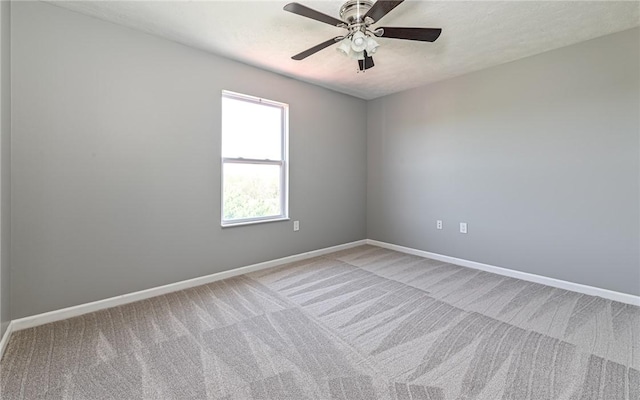 carpeted spare room with baseboards and ceiling fan