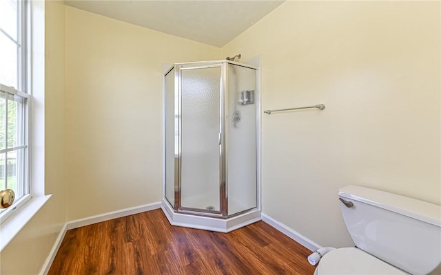 bathroom with toilet, baseboards, wood finished floors, and a stall shower
