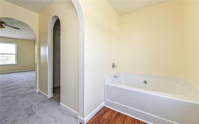 full bathroom with baseboards, ceiling fan, and a bath