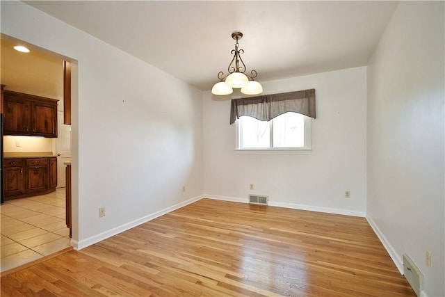 unfurnished dining area with baseboards, visible vents, and light wood finished floors