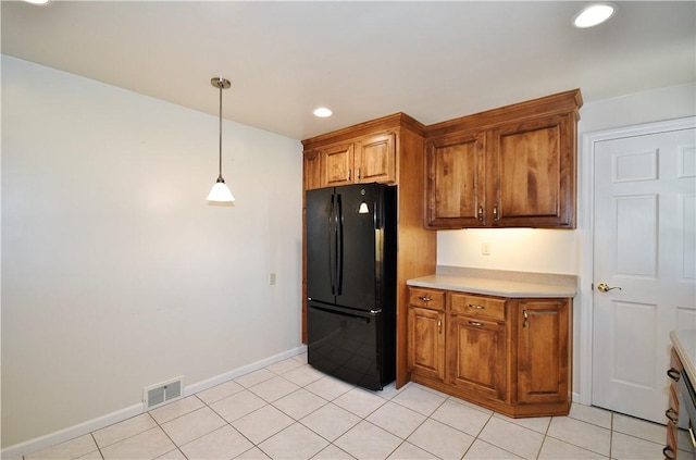 kitchen featuring brown cabinetry, decorative light fixtures, visible vents, light countertops, and freestanding refrigerator