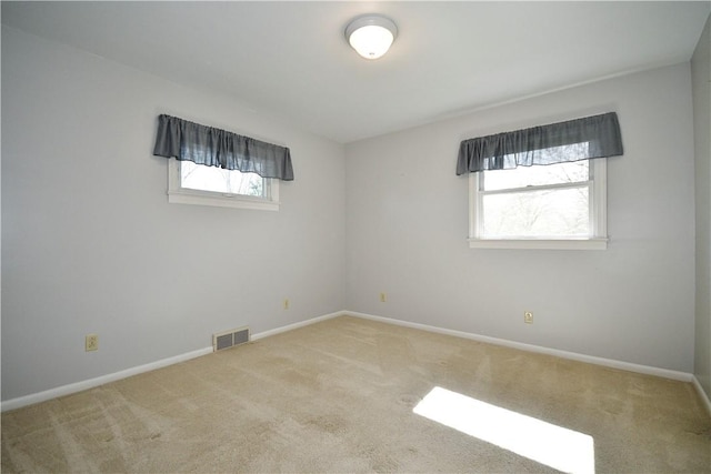 carpeted empty room featuring baseboards, visible vents, and a wealth of natural light
