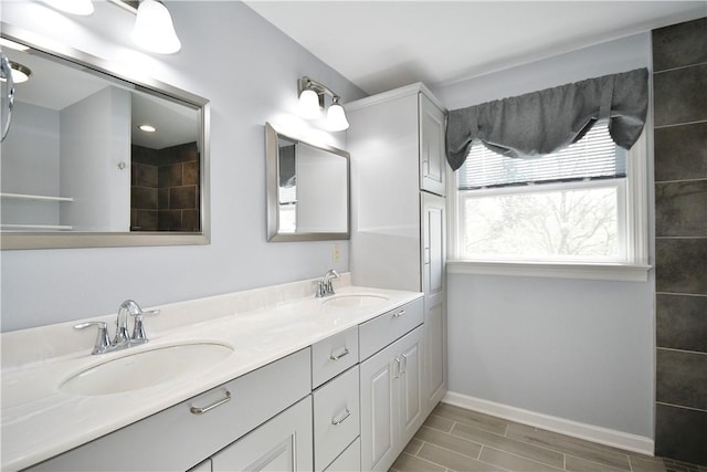 bathroom featuring a sink, wood tiled floor, baseboards, and double vanity