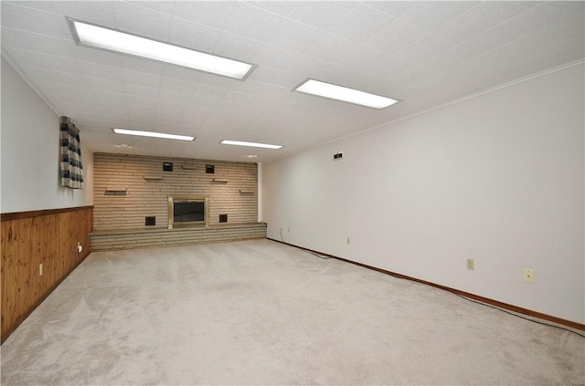unfurnished living room with carpet, a brick fireplace, wainscoting, and wooden walls