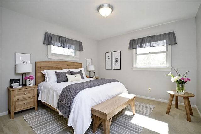 bedroom featuring baseboards, multiple windows, and light carpet