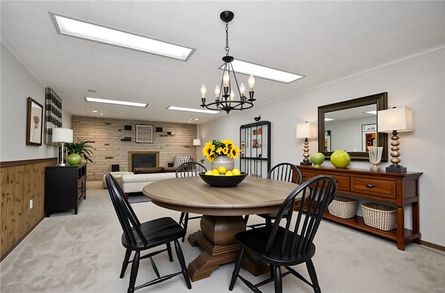 dining room featuring light colored carpet, wooden walls, a notable chandelier, and a fireplace