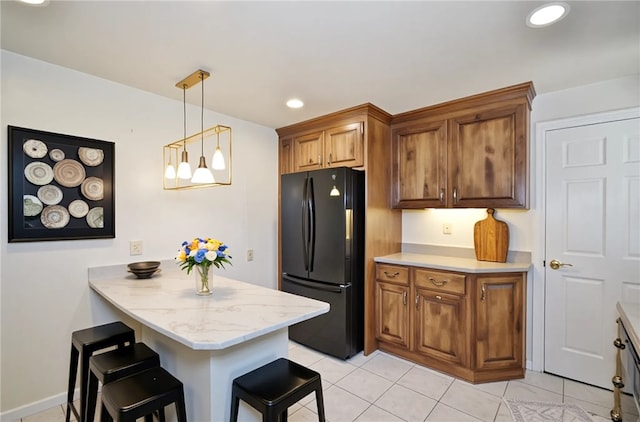 kitchen featuring brown cabinets, a kitchen breakfast bar, freestanding refrigerator, and a peninsula