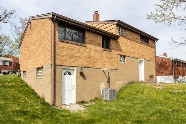 back of property with brick siding, a yard, and a chimney
