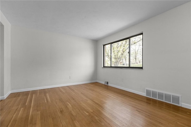 empty room with baseboards, light wood-style flooring, and visible vents