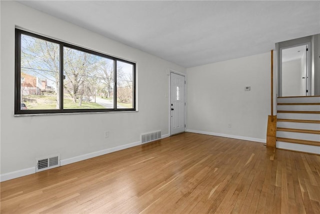 interior space featuring visible vents, light wood-style flooring, baseboards, and stairway