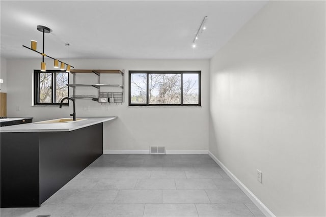kitchen featuring plenty of natural light, visible vents, open shelves, a sink, and light countertops
