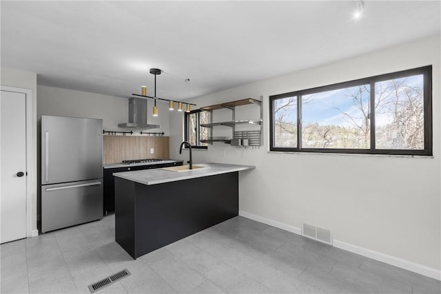 kitchen featuring visible vents, freestanding refrigerator, a peninsula, modern cabinets, and wall chimney range hood