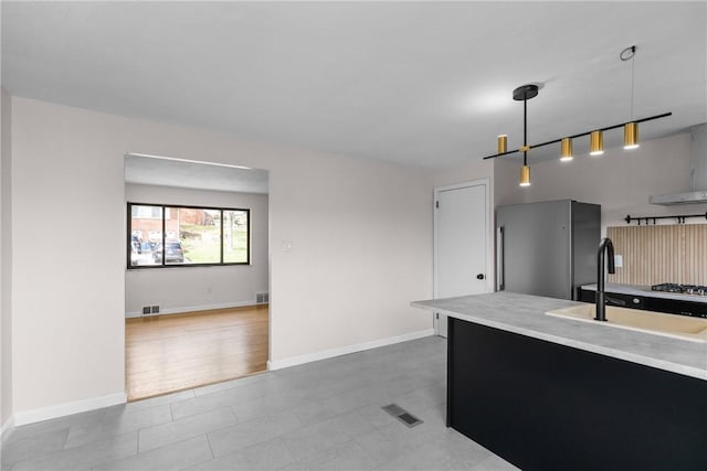 kitchen featuring visible vents, light countertops, a sink, appliances with stainless steel finishes, and decorative light fixtures